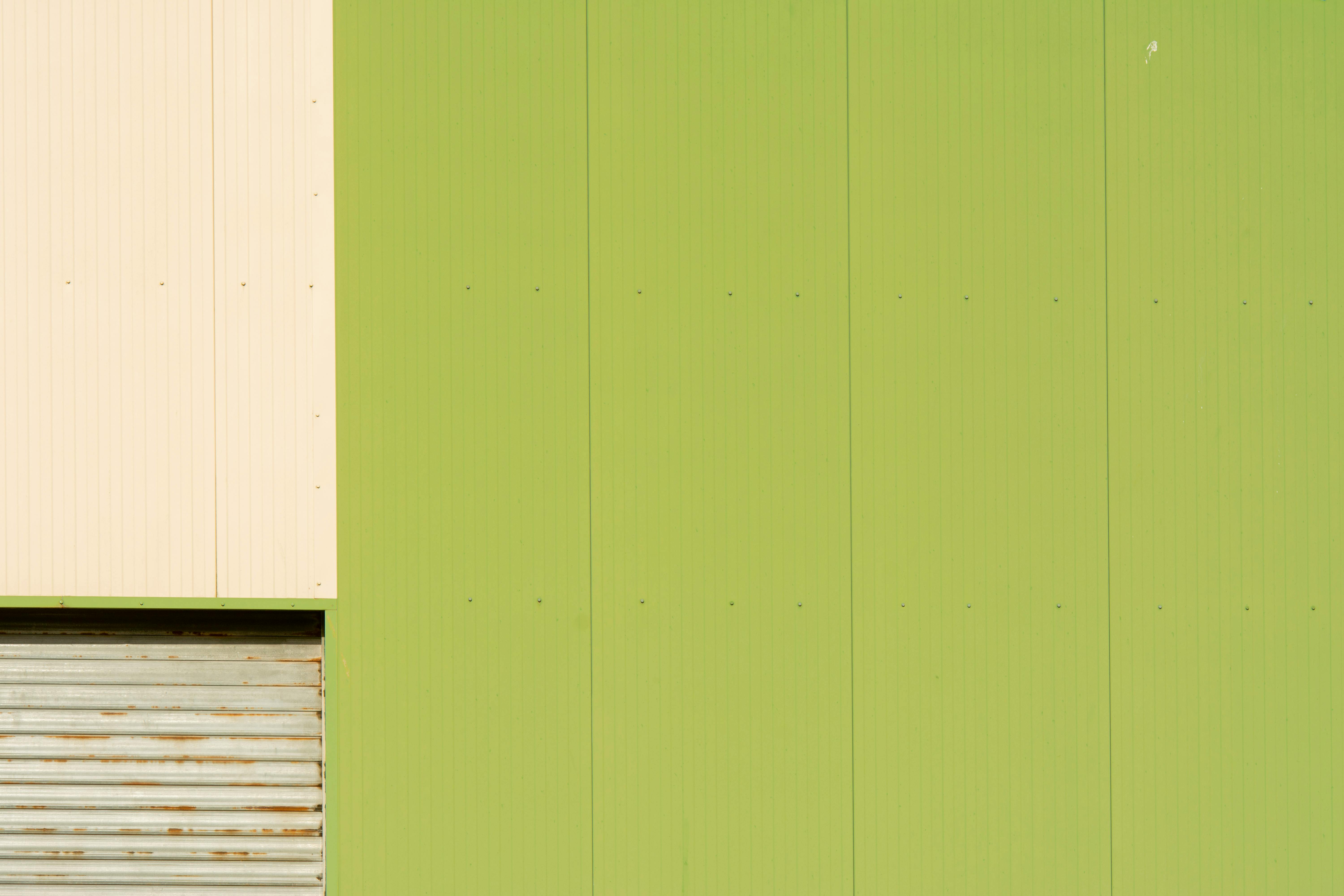 Gratis Fachada verde industrial con formas abstractas y detalle de puerta de garaje. Foto de stock