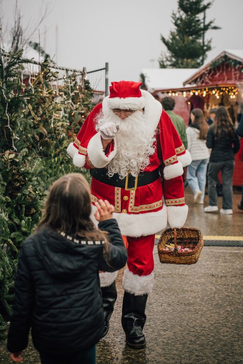 Free Santa Claus interacts with visitors at a festive Christmas market in Saint-Malo, France. Stock Photo