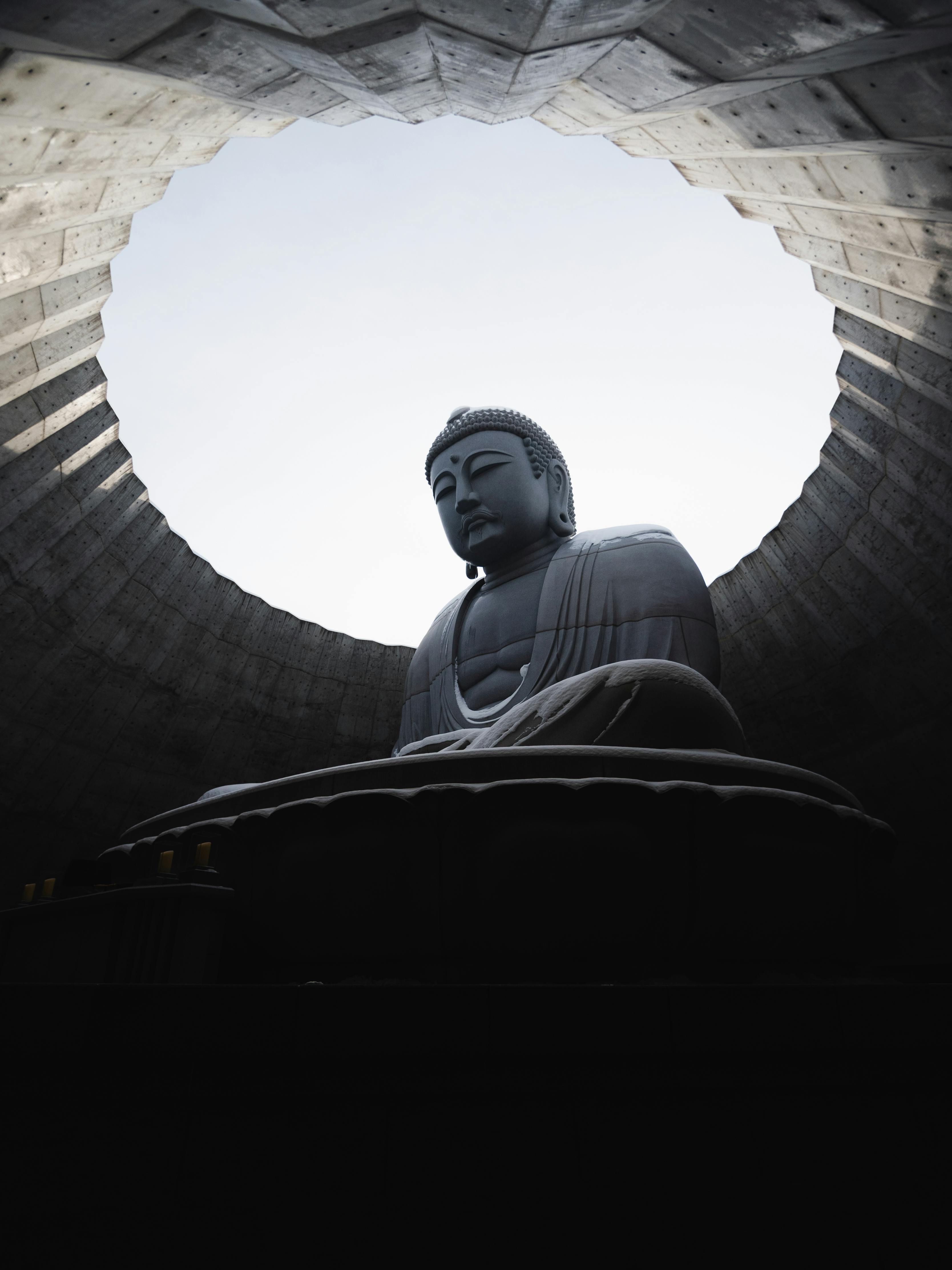 Large Buddha statue under circular opening in a serene concrete structure, Japan.