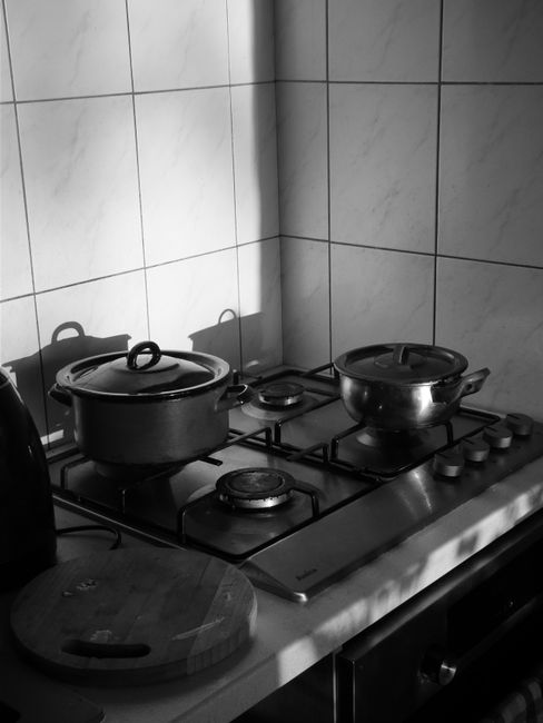 Black and white photo of a stove with cooking pots, creating a warm, homely feel.