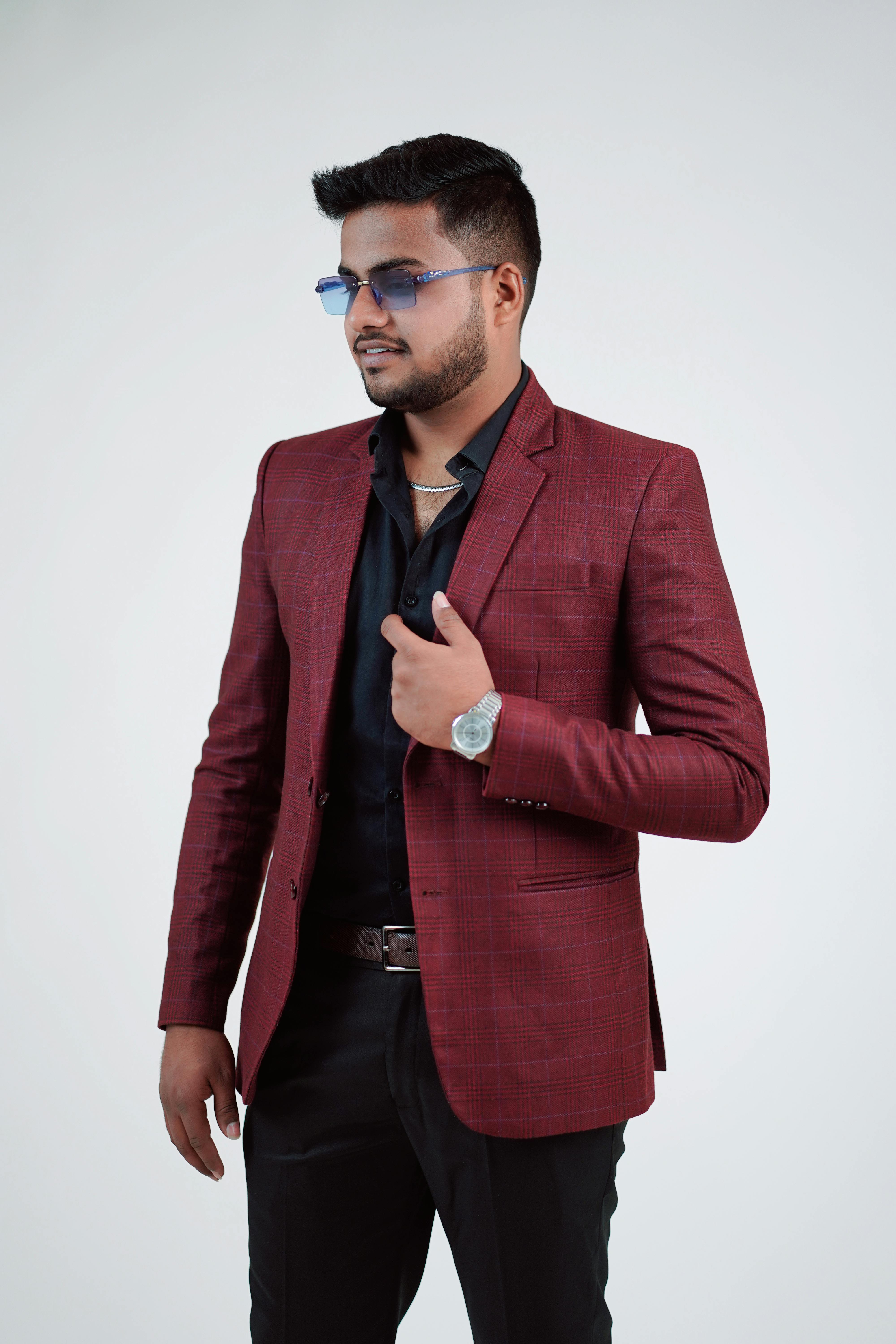 Confident man posing in a red suit with sunglasses, exuding style and elegance.
