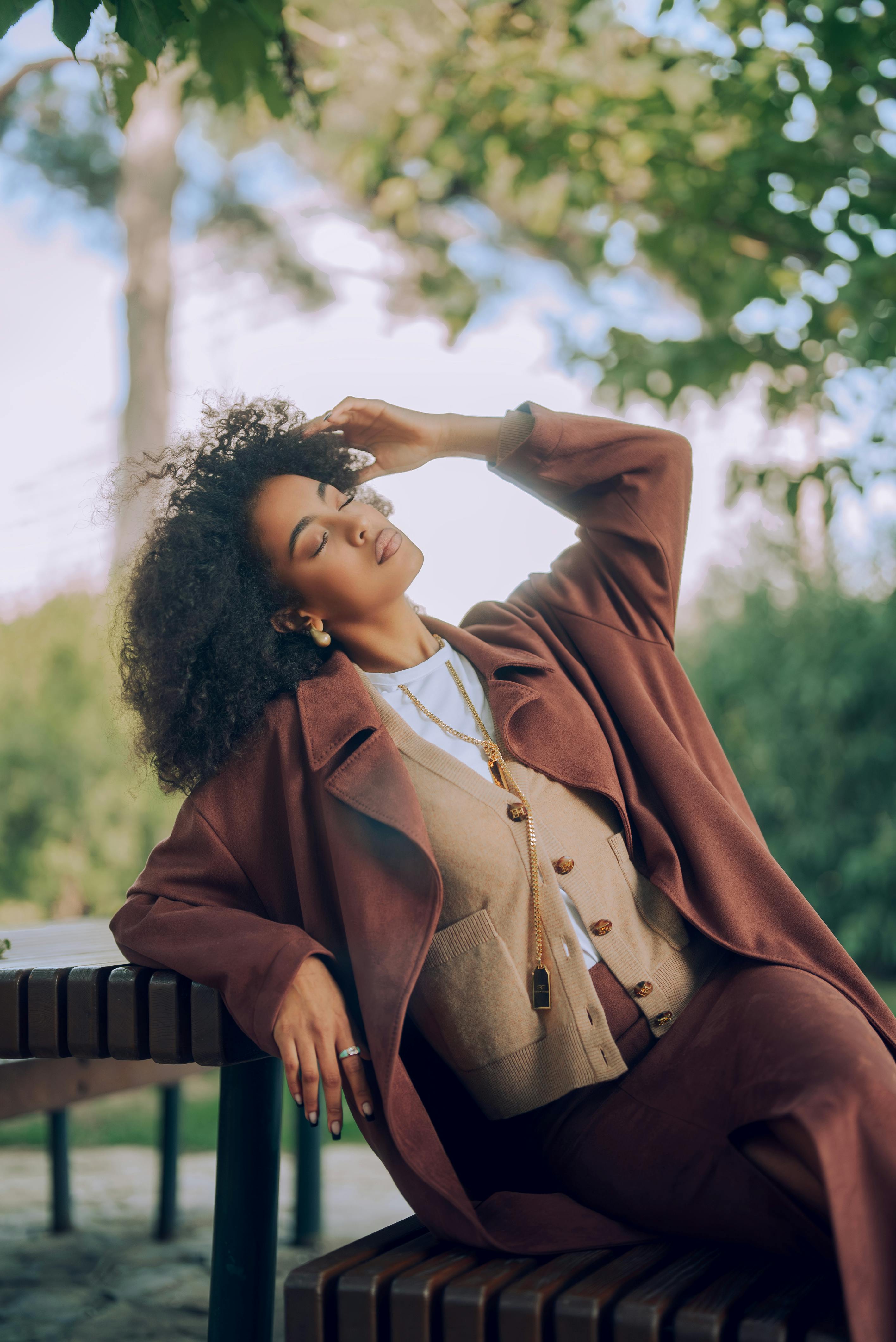 Elegant woman in autumn attire relaxing outdoors, embodying serene fashion vibes.