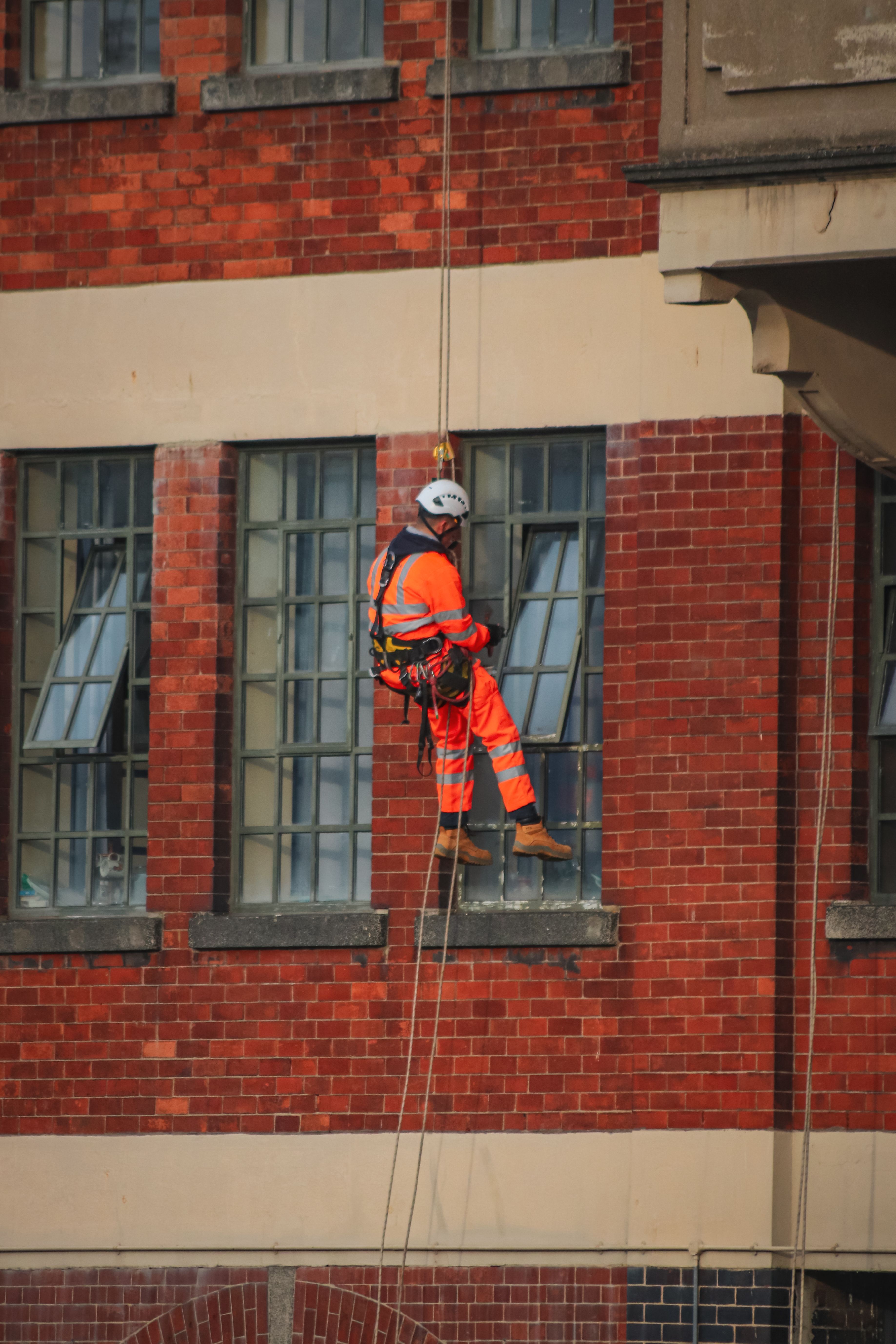 Rope access technician maintaining a brick building facade.