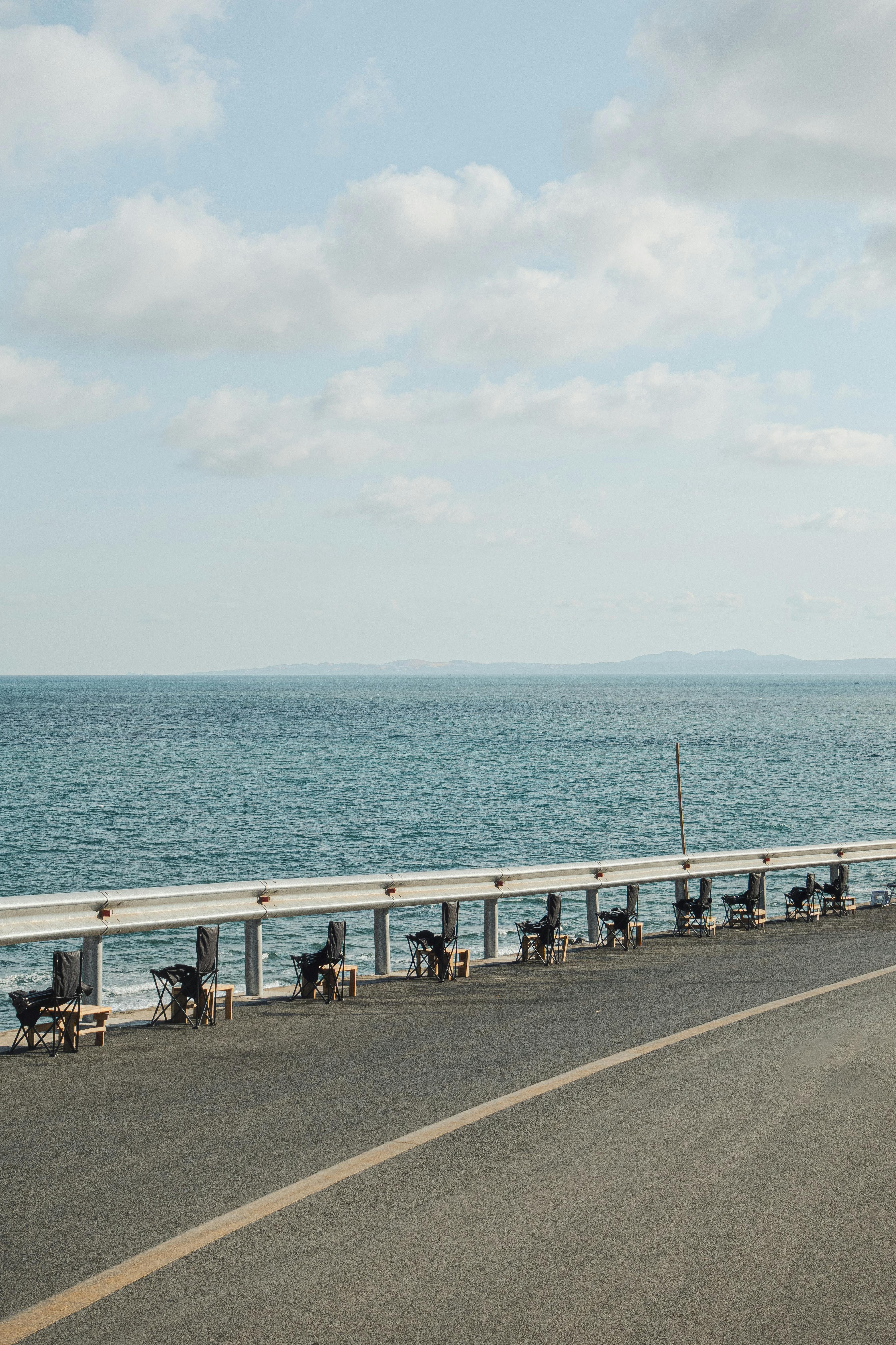 A peaceful coastal road with a clear ocean view and blue sky, perfect for travel and relaxation themes.