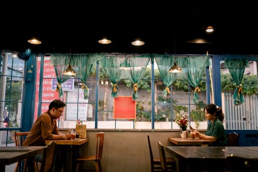 Two adults enjoying a relaxed meeting in a cozy cafe with vintage decor and soft lighting.