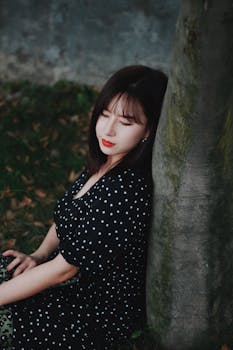 一位身穿圆点连衣裙的年轻女子在户外优雅地摆姿，散发着美丽与优雅