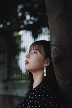 一位年轻的亚洲女子在户外优雅侧身，宁静的侧影展现出时尚与美丽