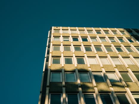 Low angle view of a modern building against a clear blue sky with striking geometric patterns.