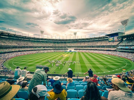 A lively cricket match at Melbourne Cricket Ground with a colorful crowd under a dynamic sky.