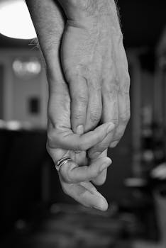 A close-up black and white image of a couple's hands intertwined, symbolizing love and connection.