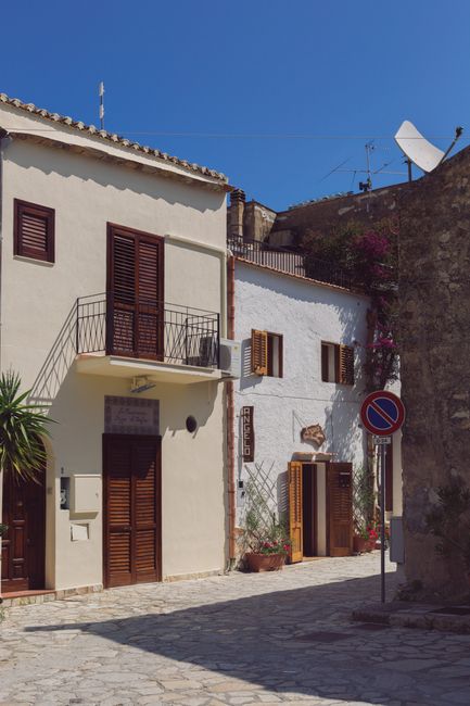 Picturesque street view in Scopello, Sicily, Italy, showcasing traditional architecture under a clear blue sky.