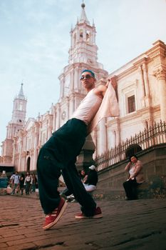 Stylish man in sunglasses strikes a pose in front of historic cathedral.