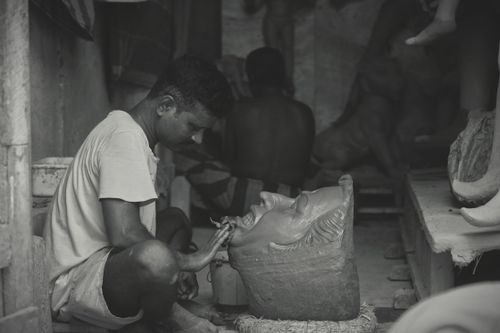 Free Black and white photo of an artisan crafting a Durga idol in a Kolkata workshop, capturing cultural artistry. Stock Photo