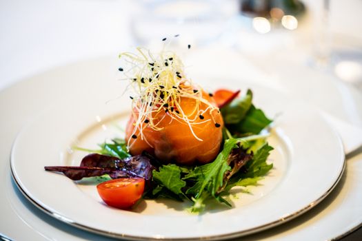 A gourmet salad featuring smoked salmon, fresh greens, and cherry tomatoes elegantly presented.