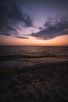 撒丁岛海岸的日落景色宁静，展现出壮观的云层与宁静的海浪