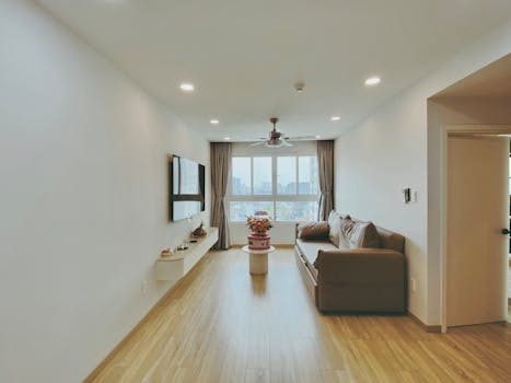 Spacious living room featuring modern decor, cozy sofa, and large city view window.