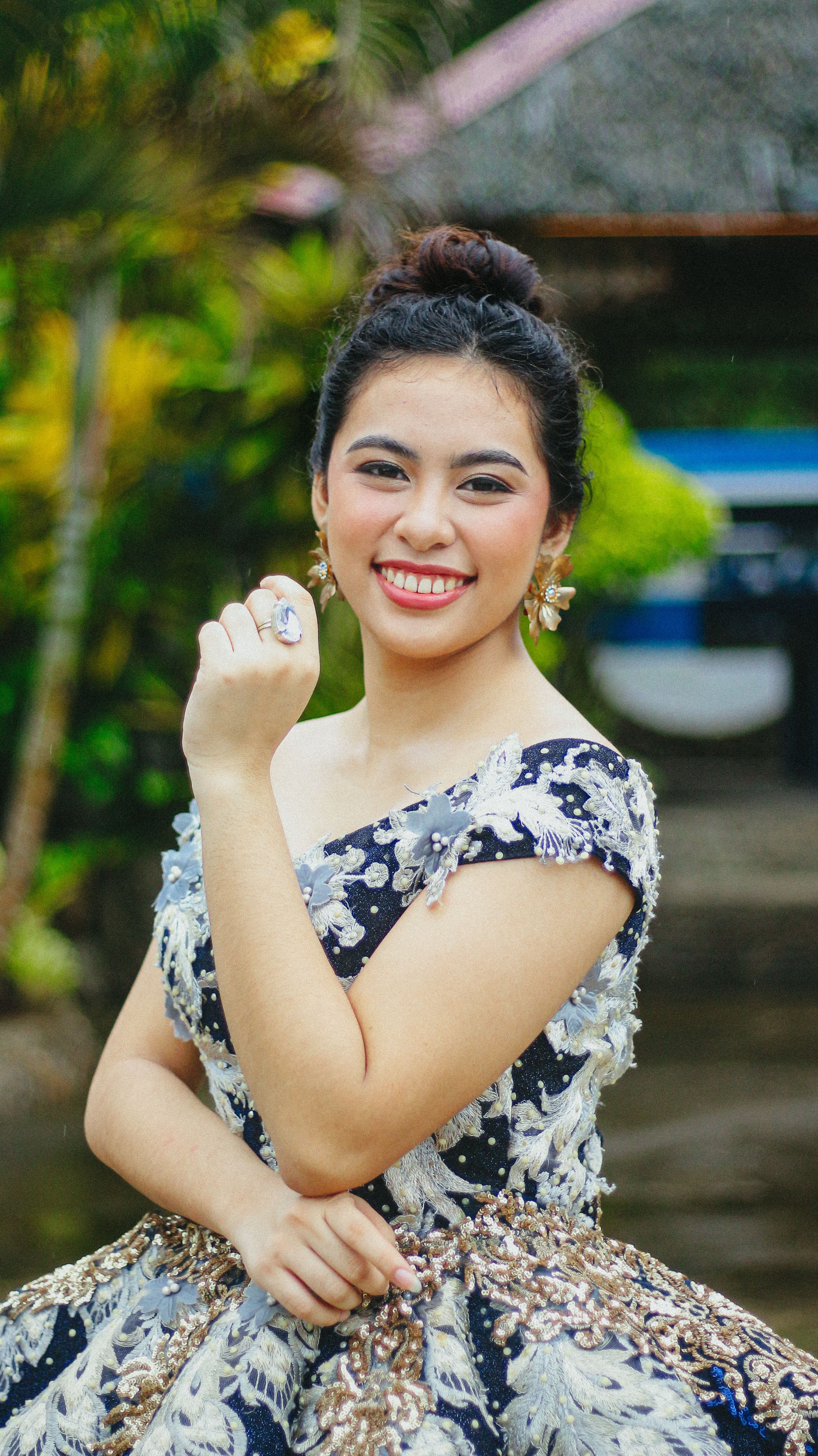 Young woman smiling in elegant dress outdoors, showcasing joy and elegance.