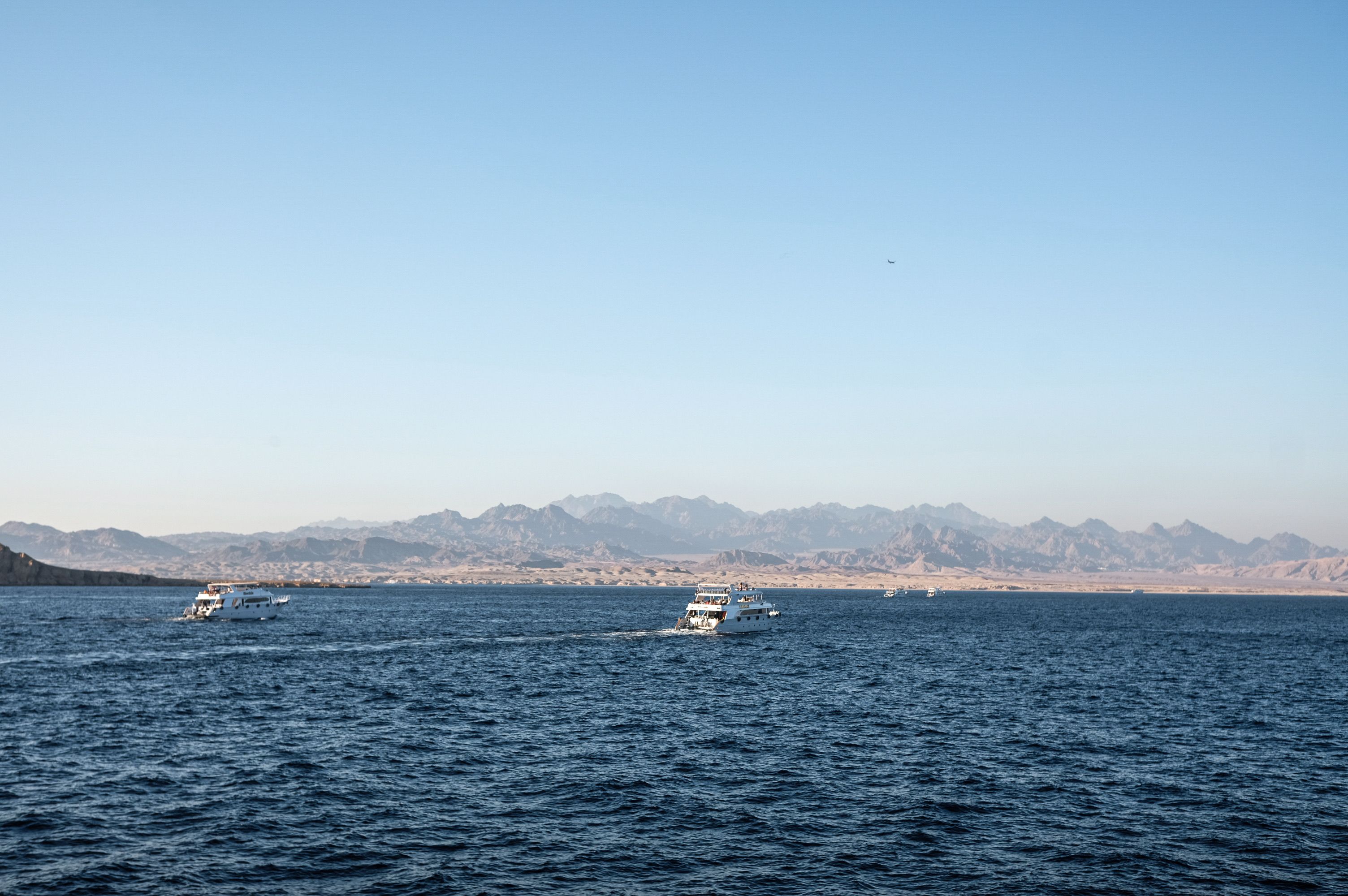 Scenic view of boats on the Red Sea with distant Egyptian mountains under a clear blue sky.