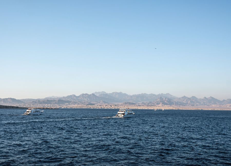 Scenic view of boats on the Red Sea with distant Egyptian mountains under a clear blue sky.