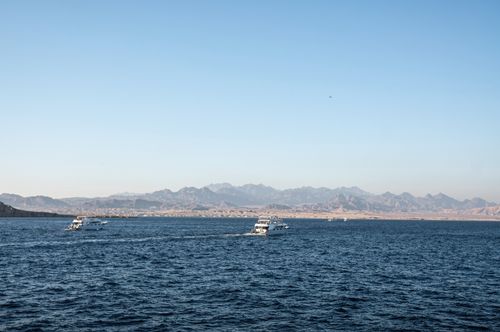 Free Scenic view of boats on the Red Sea with distant Egyptian mountains under a clear blue sky. Stock Photo