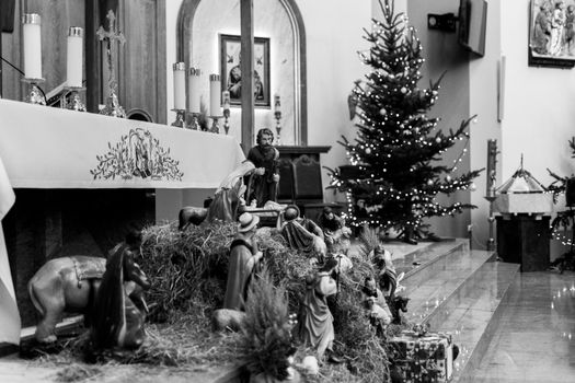 A black and white photo of a nativity scene inside a church decorated for Christmas.