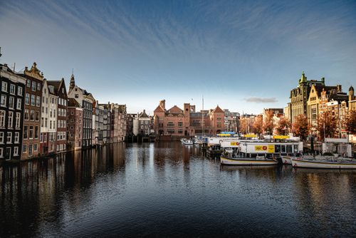 Free Charming canal view highlighting Amsterdam's historic architecture and picturesque setting. Stock Photo