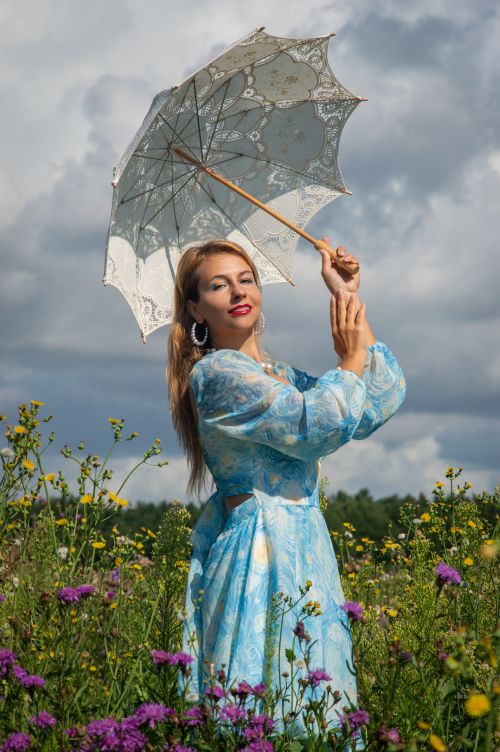 Free Elegant woman in floral field holding a lace umbrella. Bright, summer day. Stock Photo