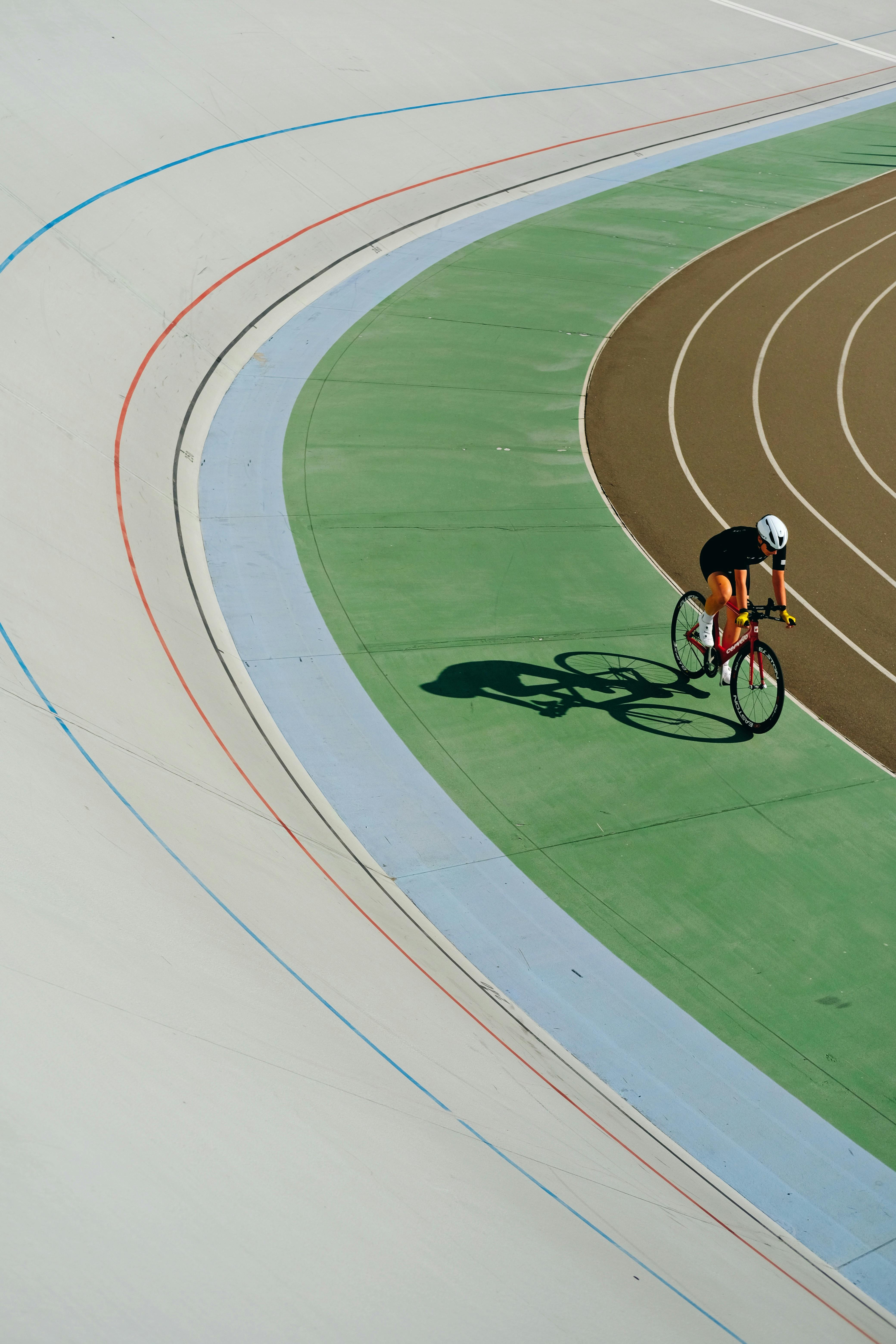 Cyclist wearing helmet races on a colorful outdoor velodrome track in Kyiv, Ukraine.