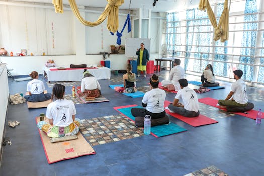 Group of adults attending a yoga class in a spacious, modern studio with an instructor.