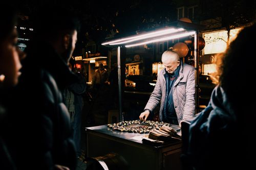 Free A street vendor selling roasted chestnuts at night under bright lights. Stock Photo