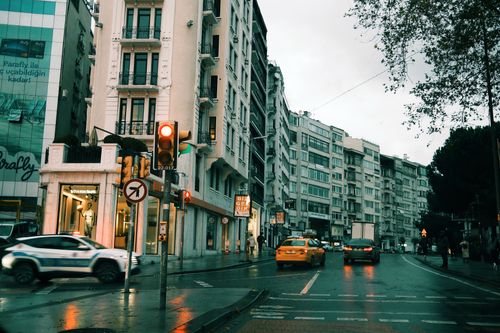 Free City scene with moving traffic, wet streets, and towering buildings at dusk in an urban area. Stock Photo
