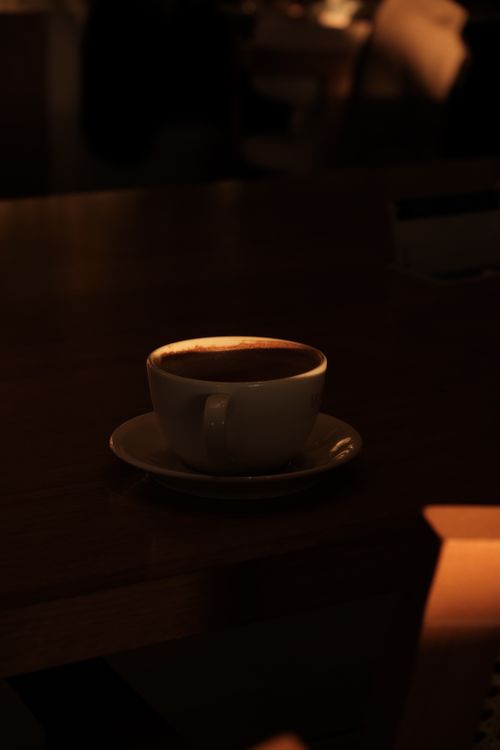 Free A solitary coffee cup in a dimly lit environment with warm evening light. Stock Photo
