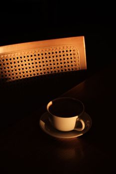 A white coffee cup in warm evening light creates a moody atmosphere.