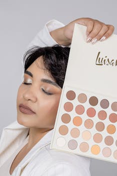 Elegant portrait of a woman showcasing a large eyeshadow palette.