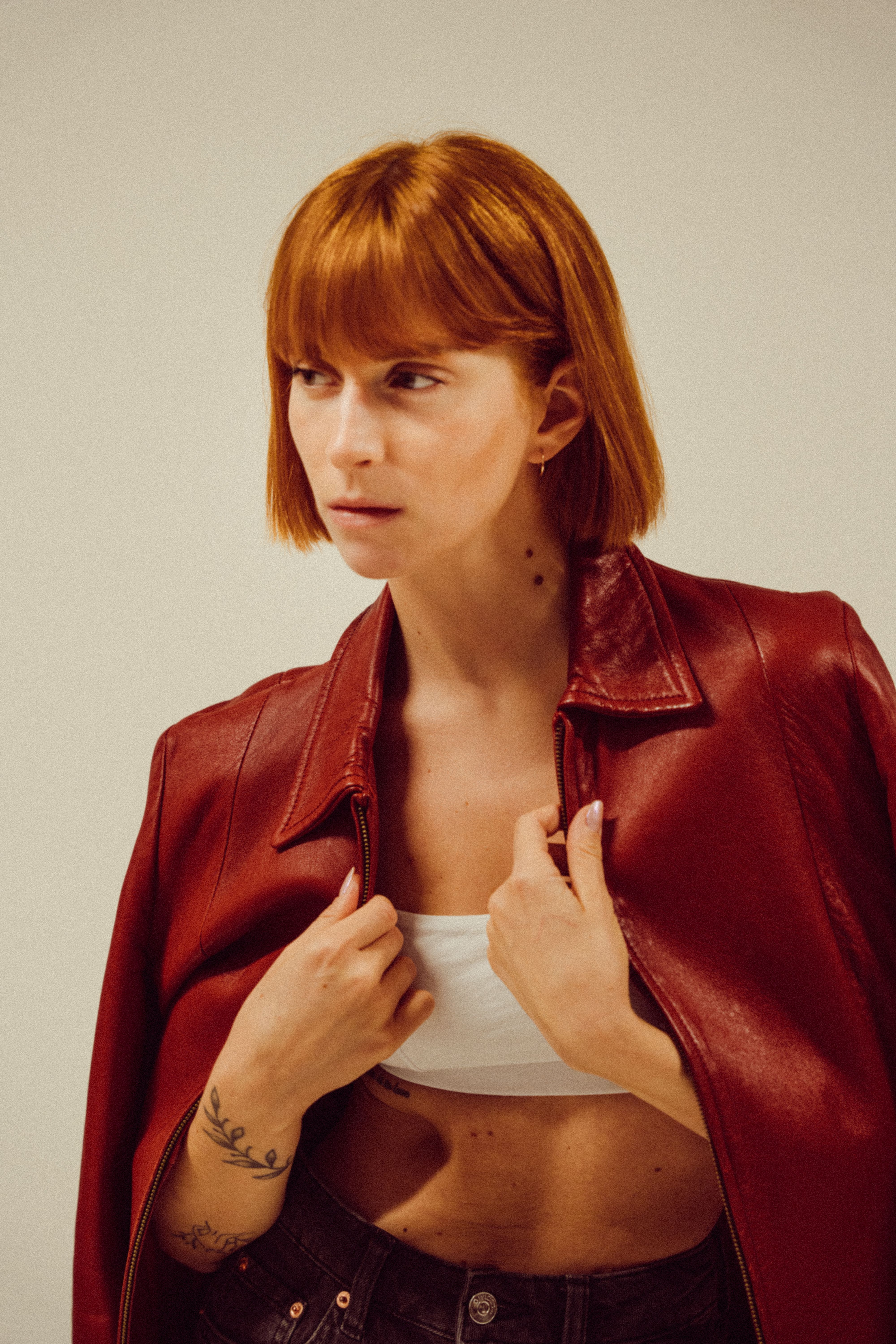 Fashionable adult woman with red hair wearing a red leather jacket and white top. Elegant modern portrait.