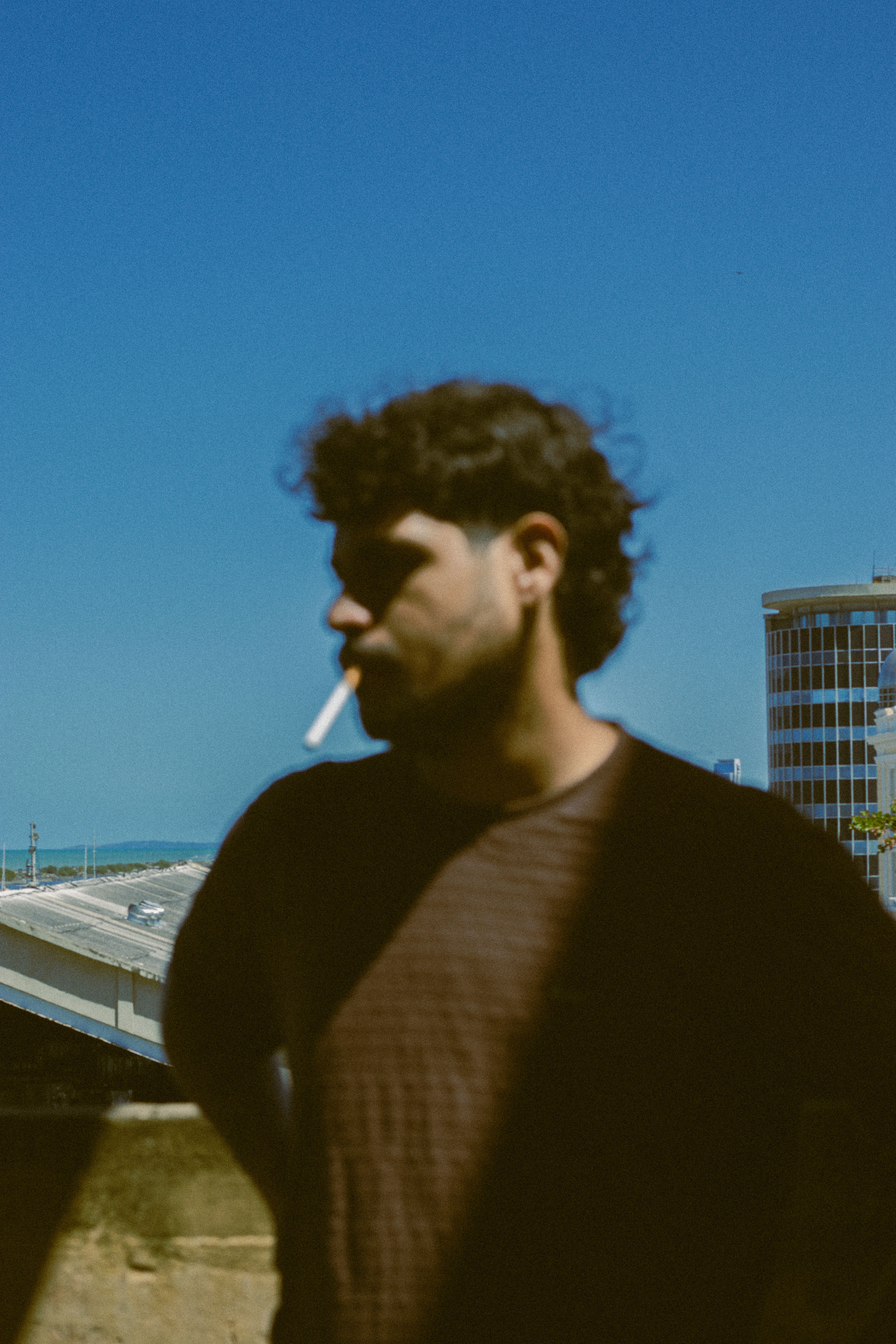 Blurred silhouette of a man smoking, with urban skyline backdrop.