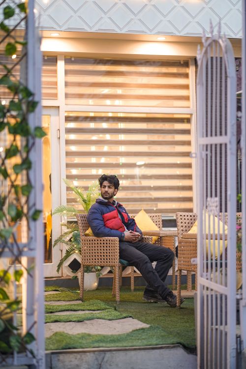 Free A man sitting in a cozy outdoor cafe surrounded by plants, enjoying a relaxing moment. Stock Photo
