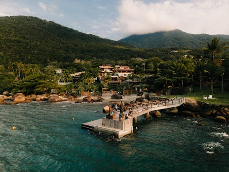 A scenic aerial view of a coastal jetty, lush greenery, and tranquil waters.