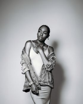 Stylish black and white portrait of an elegant woman in a denim jacket and dress.
