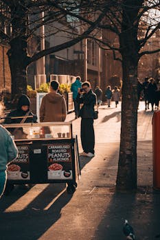 Busy London street with people and a snack vendor in the afternoon light.