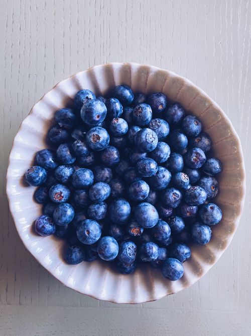 Free Top view of fresh blueberries in a white ceramic bowl on a table. Stock Photo