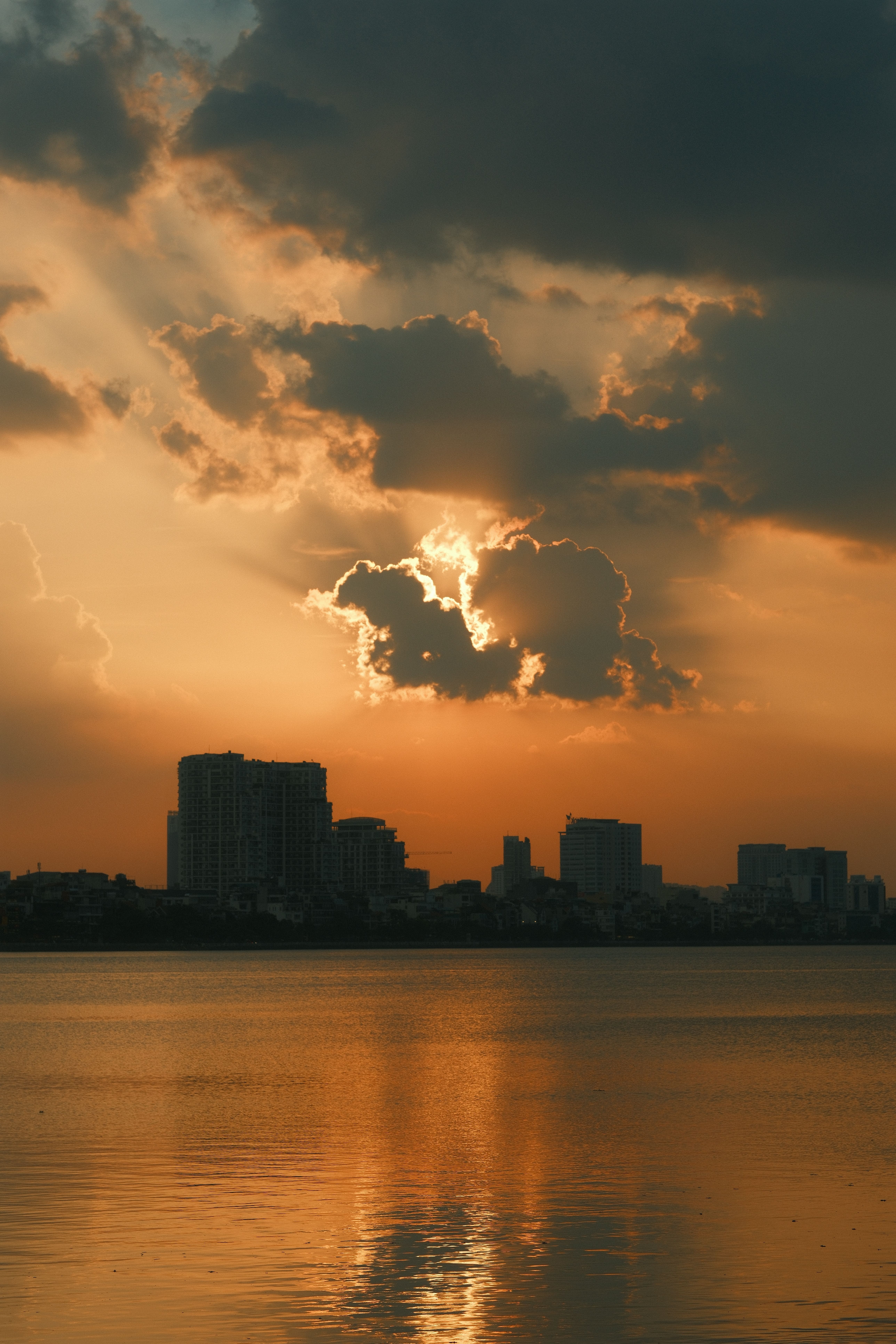 Dramatic Sunset Over City Skyline Reflecting on Water · Free Stock Photo
