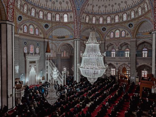 Free A beautiful mosque interior filled with people, showcasing intricate architectural details and large chandelier. Stock Photo