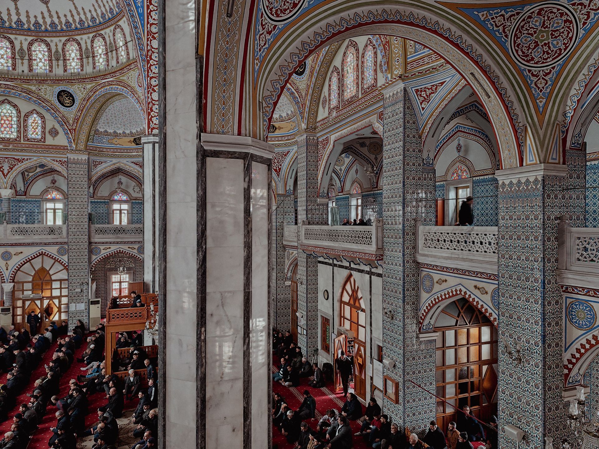 Vibrant interior of a mosque filled with worshippers, showcasing Islamic architectural beauty.