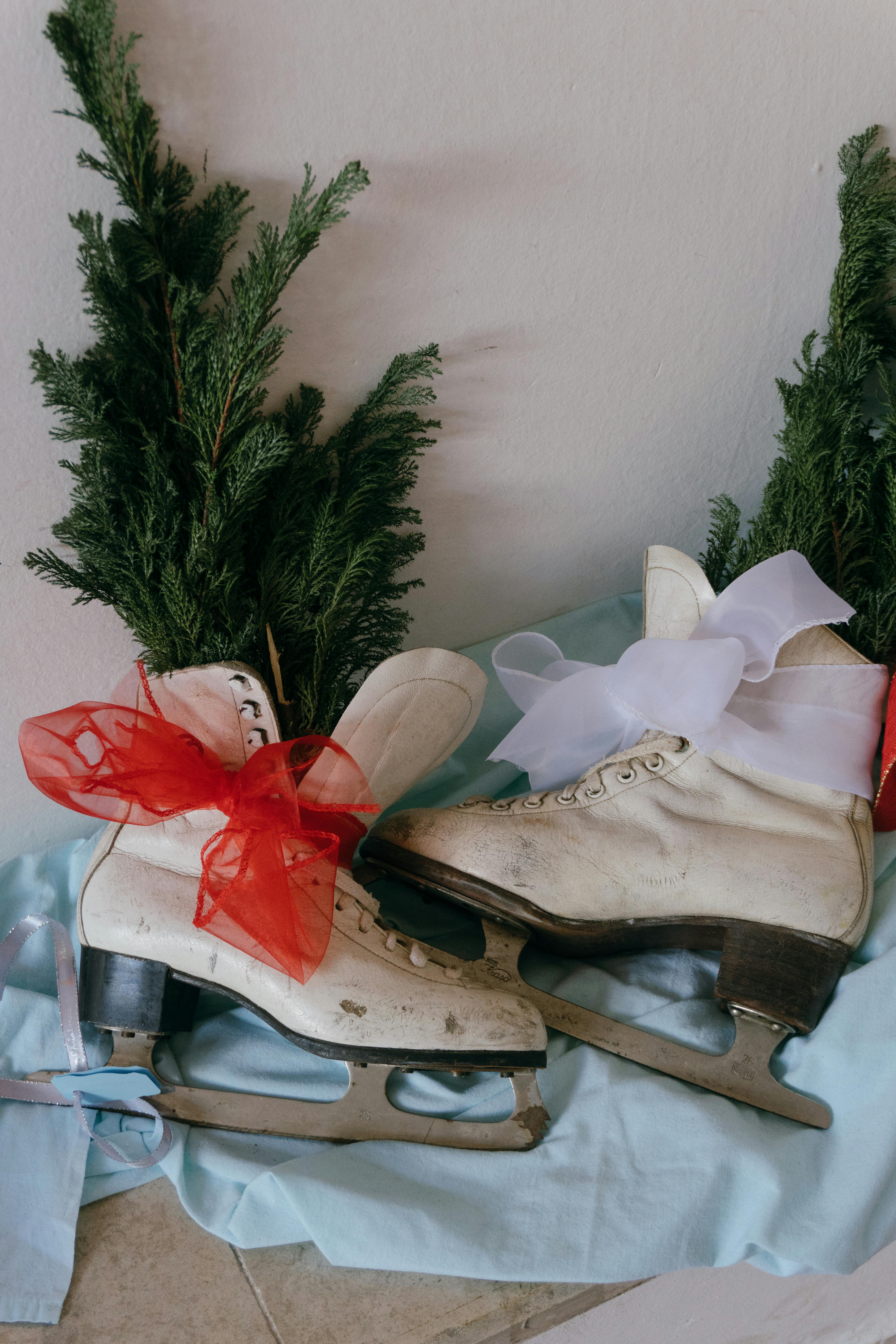 Vintage ice skates with festive ribbons and evergreen branches, perfect for winter decor.