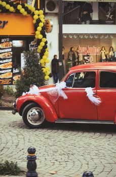 Classic red car adorned with white ribbons, perfect for wedding themes.