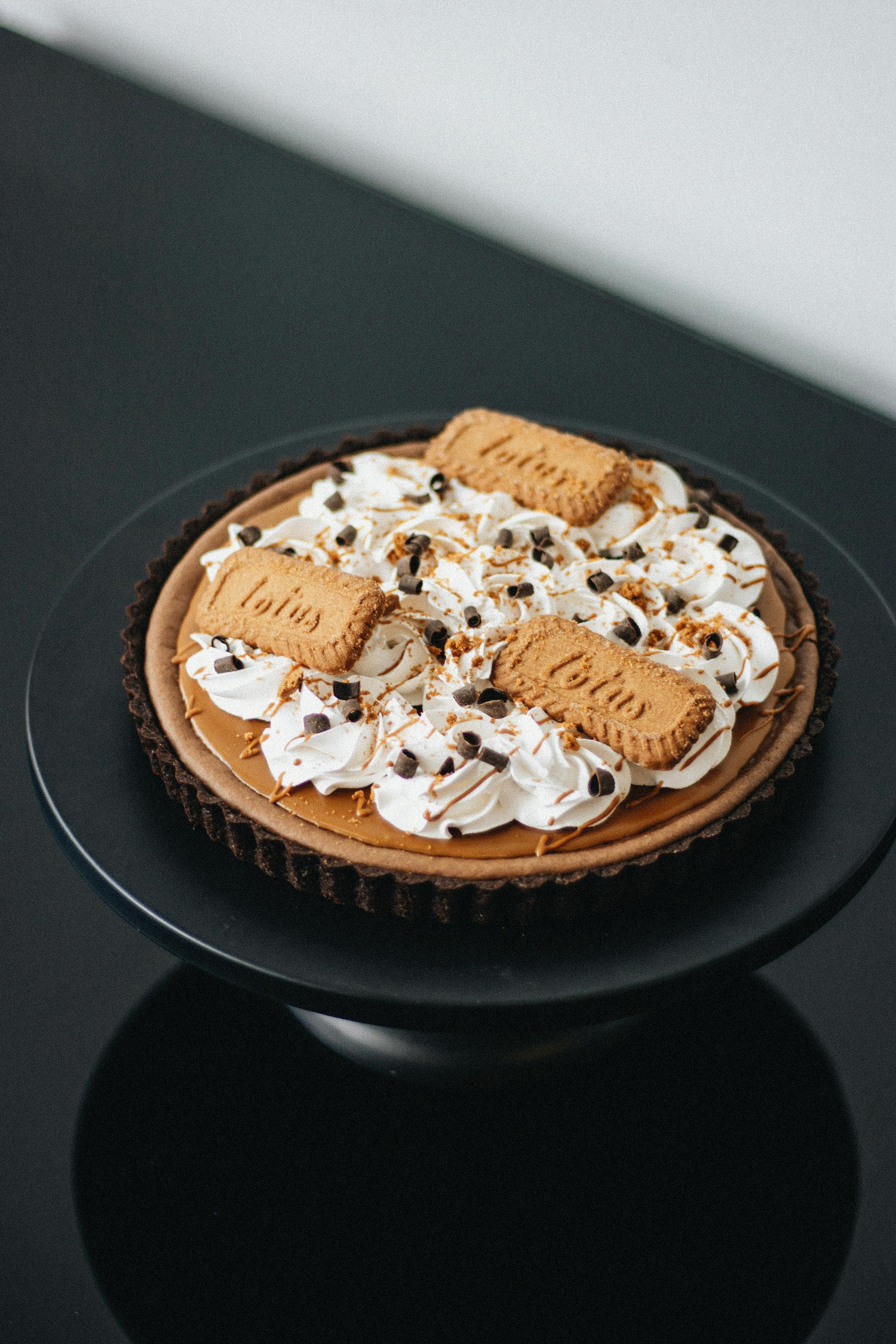 Indulge in this elegant chocolate tart topped with cream and biscuits, perfect for dessert lovers.