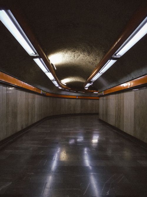 Free A dimly lit underground tunnel with orange accents and fluorescent lights creating a moody atmosphere. Stock Photo