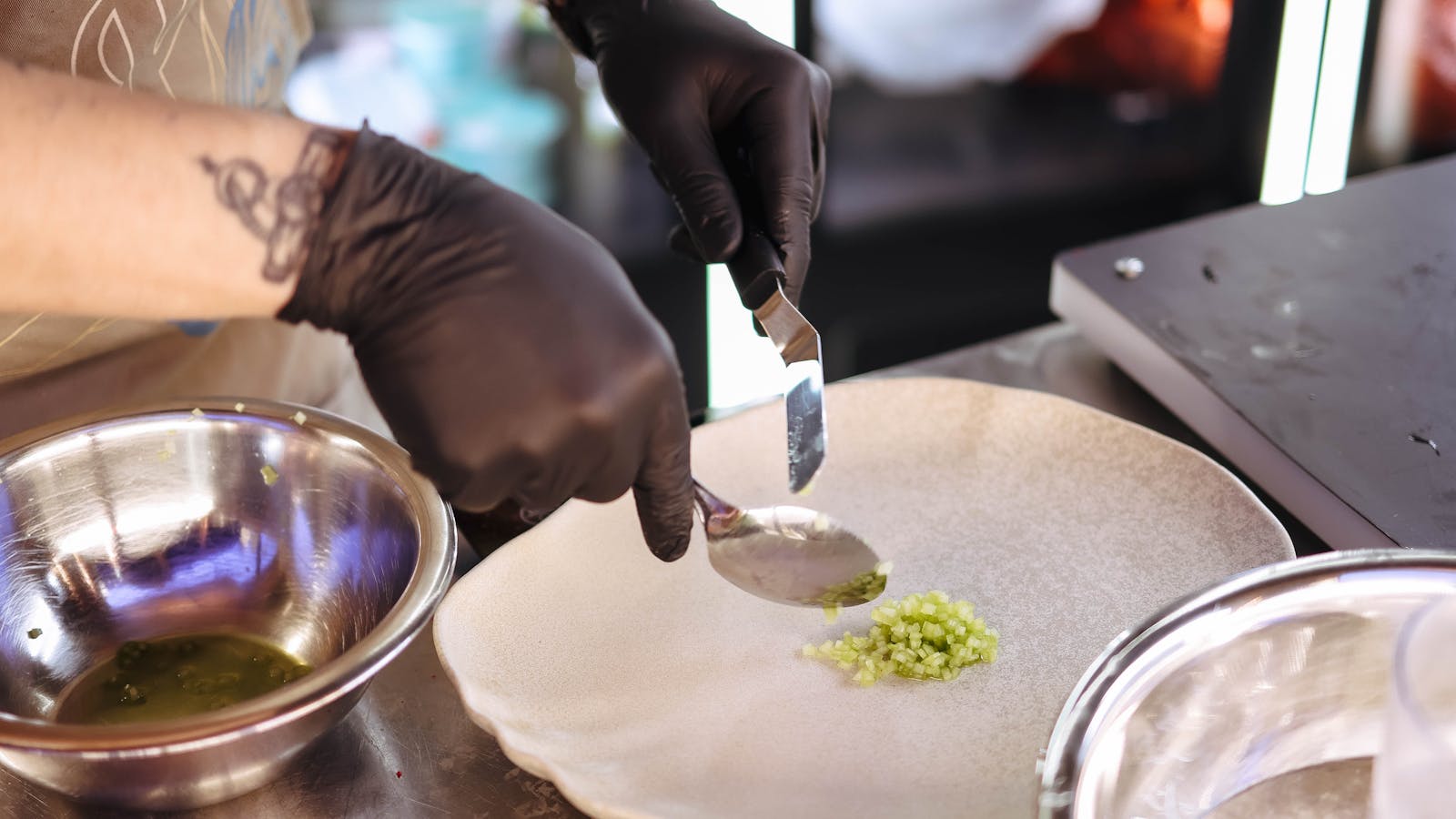 Chef en cuisine dressant une assiette gastronomique dans un restaurant, focus sur la précision du geste