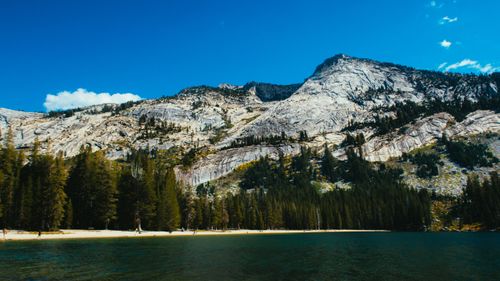Free Breathtaking view of a mountain lake surrounded by towering peaks and lush forest under a clear blue sky. Stock Photo